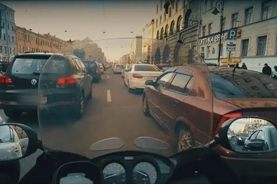 Вид с мотоцикла на плотную городскую пробку между рядами машин